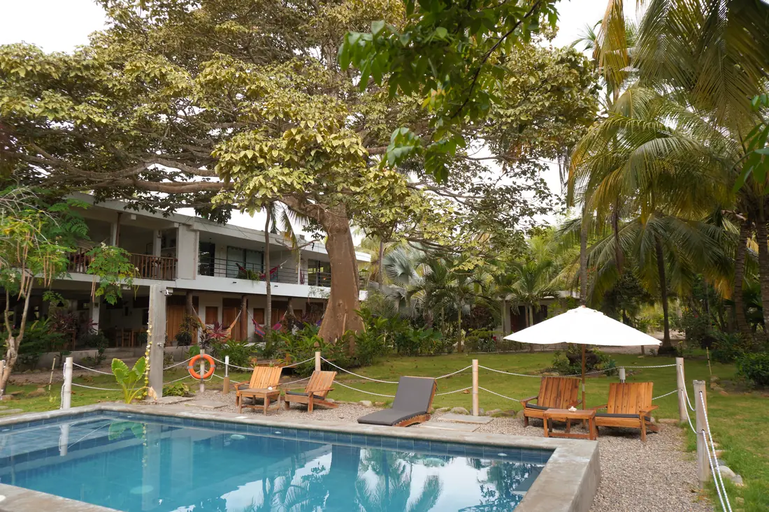 Casa Chapolín en Palomino: cabañas de dos pisos entre palmeras, con piscina y jardín en primer plano.